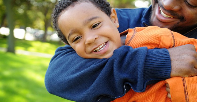 Smiling child being hugged by smiling man