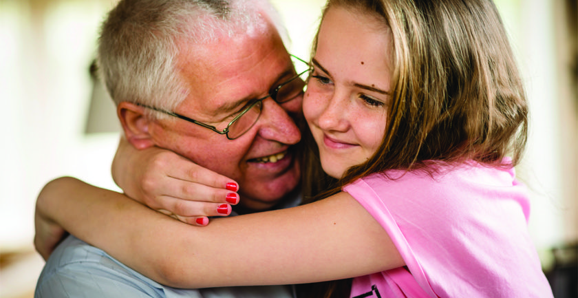 Young girl in pink top hugging smiling man
