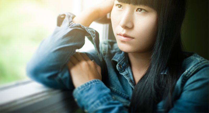 Teenage girl leaning against window