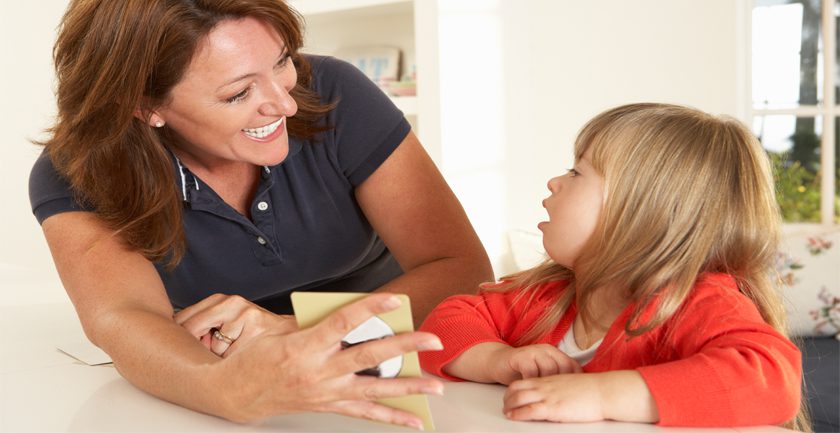 Young girl being shown card by smiling woman