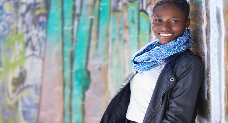 Teenage girl smiling leaning against wall