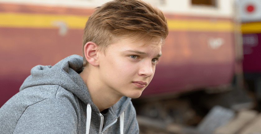 Teenage boy wearing grey hooded top