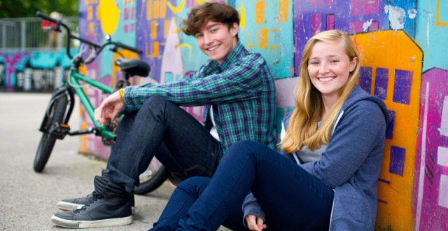 teen-girl-and-boy-sitting-against-a-graffitti-wall