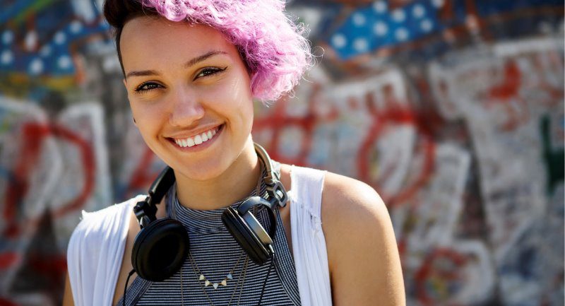 smiling-young-hipster-girl-posing-against-graffiti-wall