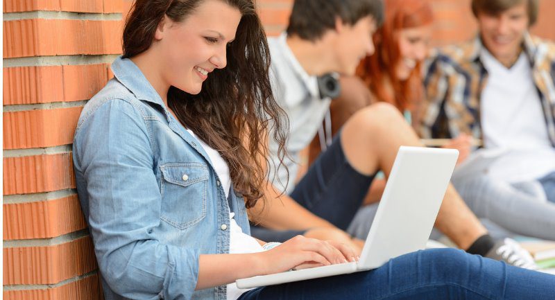 student-girl-with-laptop-and-friends-outside