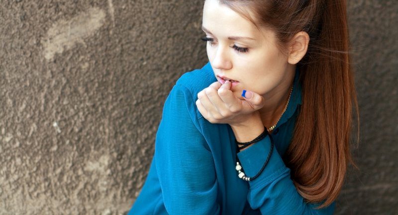 girl-in-a-blue-shirt-sitting-against-a-concrete-wall-picture-id465043902