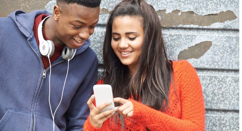 teenager couple sharing text message on mobile phone