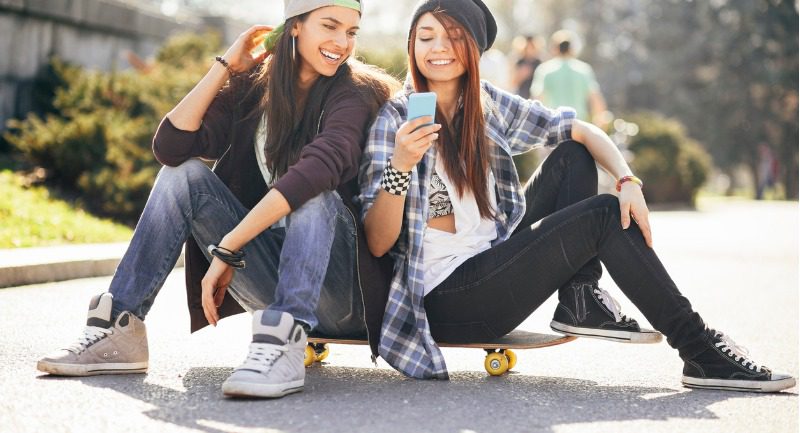 teenage-girls-with-smart-phone-and-skateboard