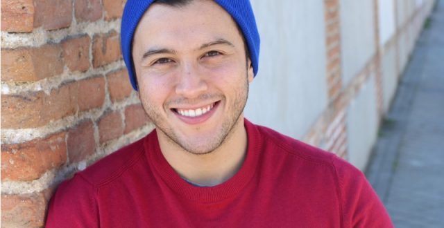 A young man in a blue hat and red t-shirt smiling