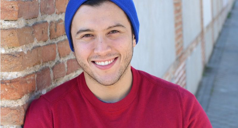 A young man in a blue hat and red t-shirt smiling