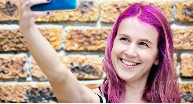 laughing-young-woman-taking-selfie-of-her-magentapink-hair