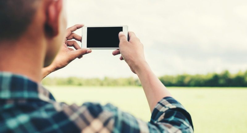 young-hipster-man-using-smartphone-taking-the-landscape-photography