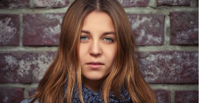 young-girl-with-brown-straight-hair-next-to-brick-wall