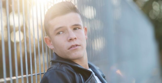 portrait-of-a-teenager-standing-against-a-fence