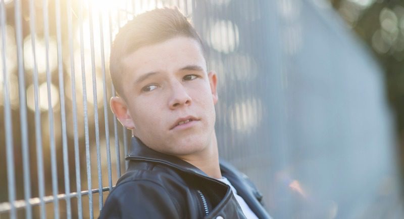 portrait-of-a-teenager-standing-against-a-fence