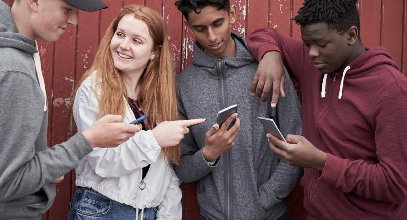 group of teenage friends looking at mobile phones