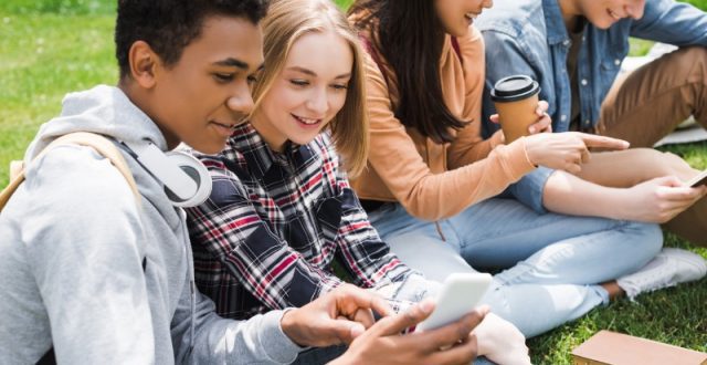 A teenage boy and a teenage girl looking at a mobile phone