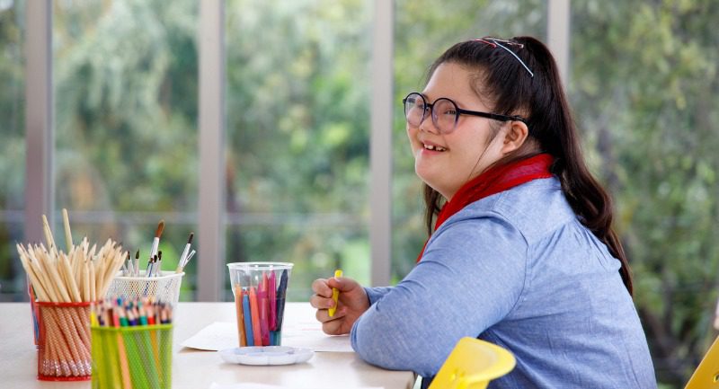 Girl with downs syndrome sitting in an art class