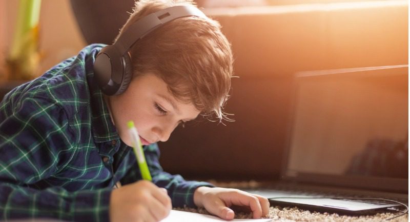 Young boy listening to music on headphones while drawing a picture