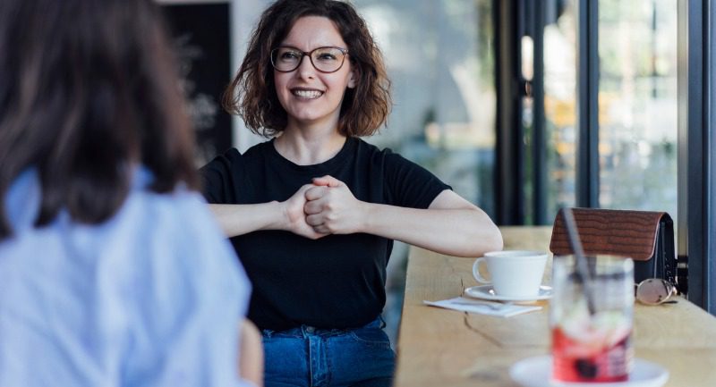 Two young woman speak to each other using sign language