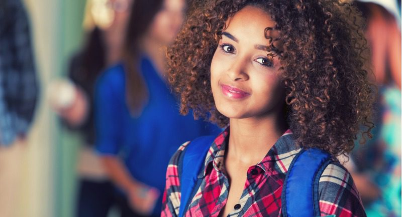 Young woman with a blue rucksack smiling at the camera