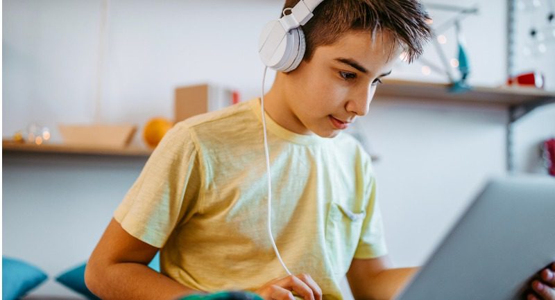 Young boy wearing headphones while using a laptop