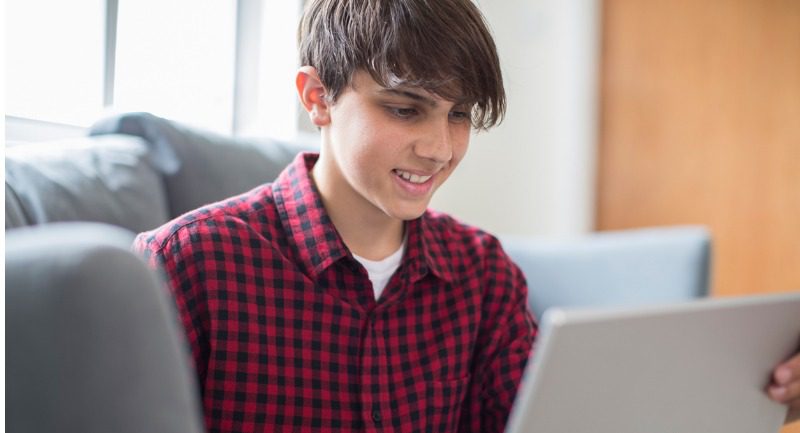 Teenage boy using a laptop at home