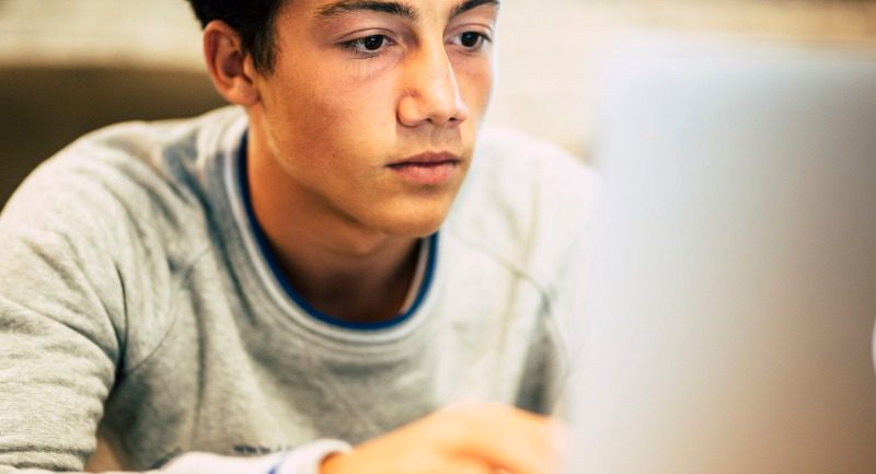 Teenage boy using a laptop at home