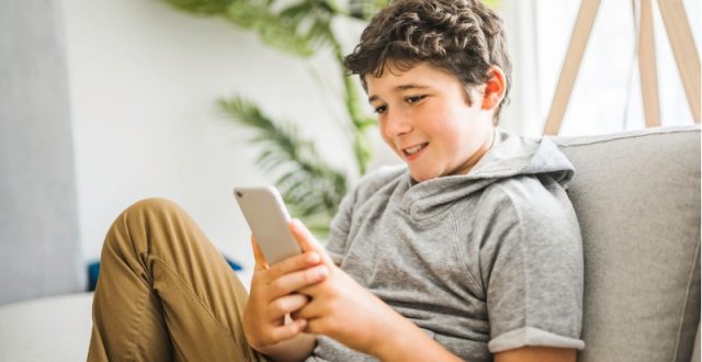 Teenager using his phone on a couch