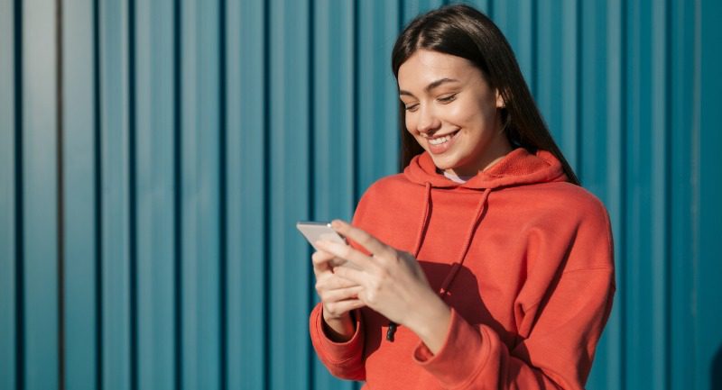 Young woman in a red jumper using a phone