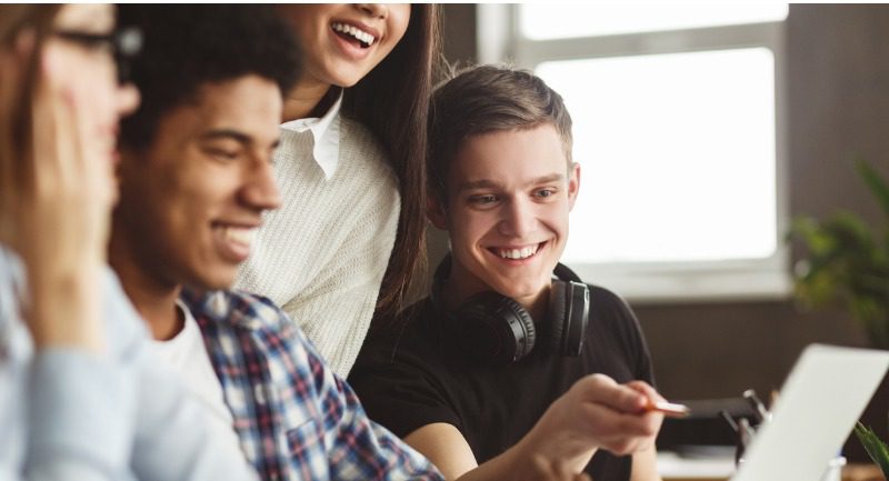 Group of students crowded around a laptop