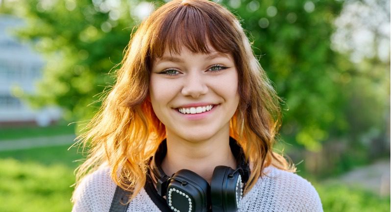 Teenage woman with long hair smiling at the camera
