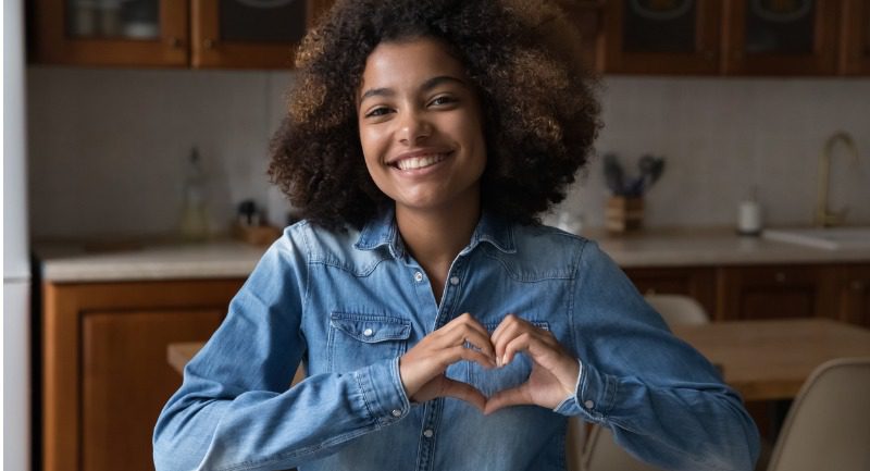 A teenage girl making a heart shape with her hands