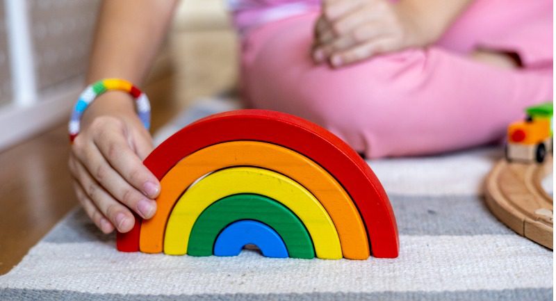 A child playing with a wooden coloured rainbow