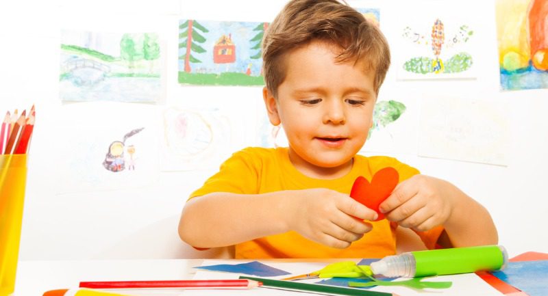 A small boy crafting a heart shape