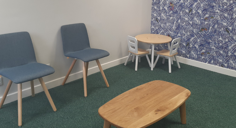 A Hearing room with 2 blue chairs and a wooden coffee table in the middle of the room