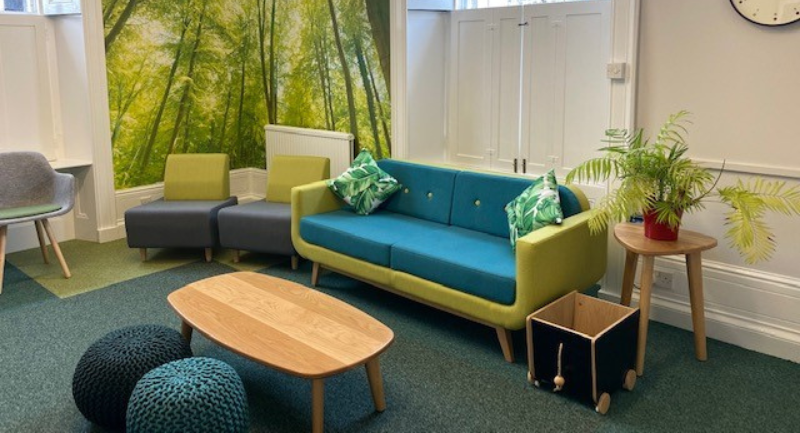 A green and blue couch with two large cushions on it