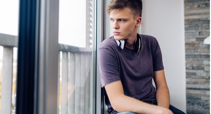 A boy looking thoughtfully out of a window