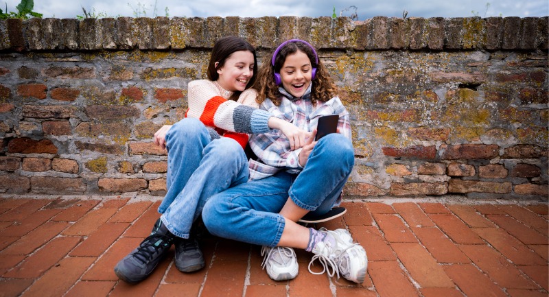 Two teenage girls looking and laughing at a smart phone