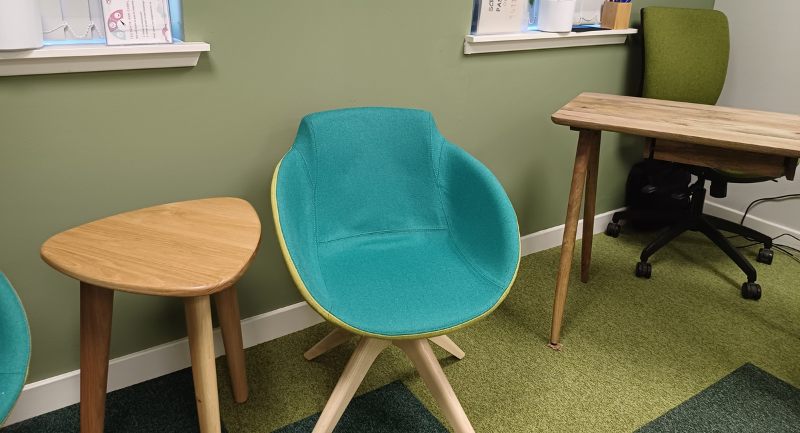 A blue and green chair with a small wooden table sitting beside it