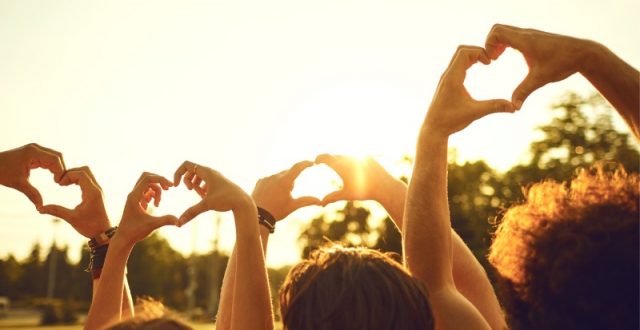 silhouettes of hands in the air making a love heart gesture