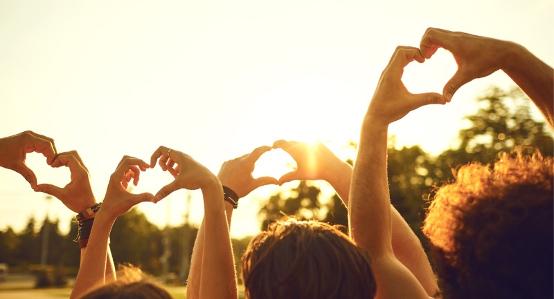 silhouettes of hands in the air making a love heart gesture