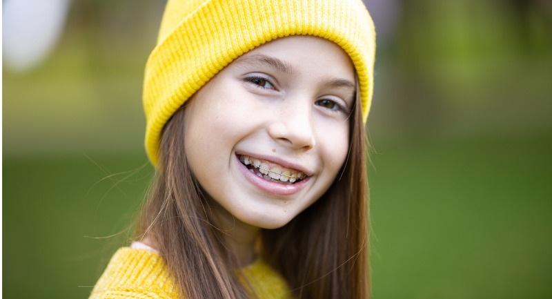 A young girl in a yellow hat smiles at the camera