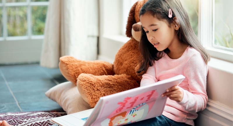 little girl reading a book at home