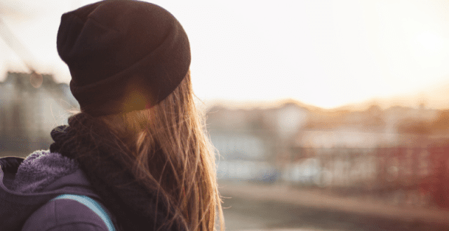 Young woman in a black hat looking at the sunset