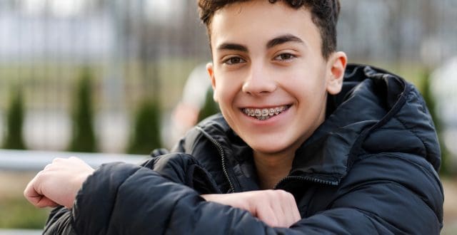 Teenage boy wearing a black jacket smiling at the camera