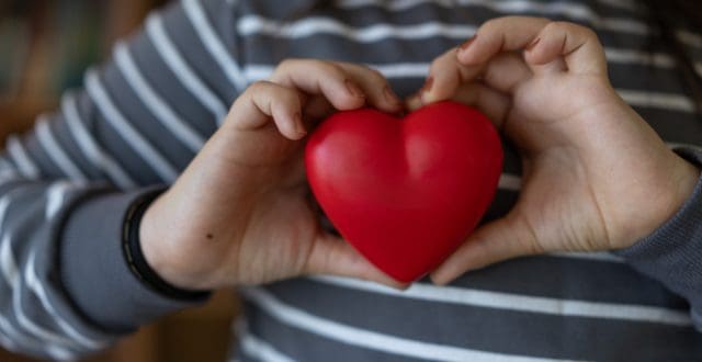 young person holding red heart showing love and care