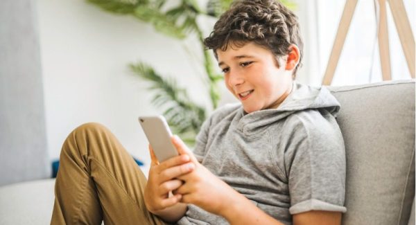 Teenager using his phone on a couch