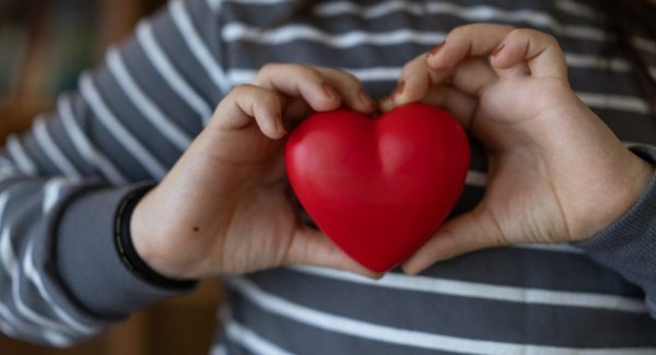 young person holding red heart showing love and care